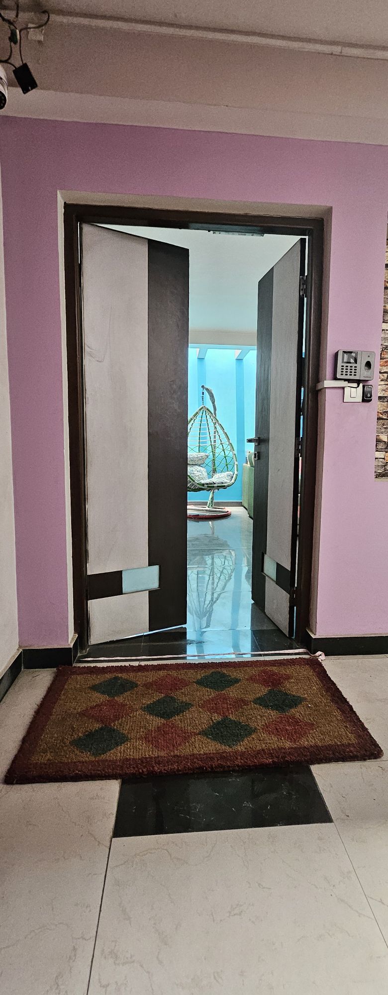 Apartment front door entrance with doormat and pink corridor