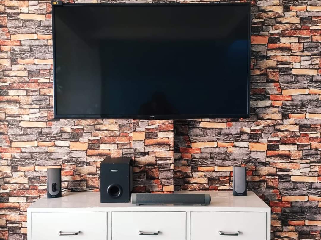Large Flat-Screen TV, Soundbar & Speakers on Brick-Pattern Wall